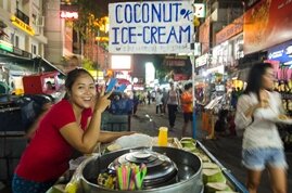Una vendedora ambulante ofrece helado de coco en una calle de Bangkok
